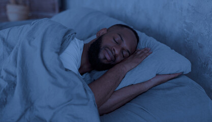 Healthy Sleeping Concept. Portrait of happy young well-slept African American man lying in bed with...
