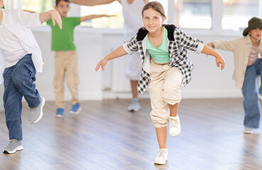 Young girl and group of positive children practicing energetic hip hop movements at modern dance...