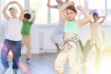 Portrait of confident tween girl hip hop dancer training during group dance class in modern dance...