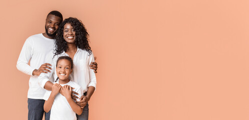 Happy Family Of Three Hugging Posing Over Yellow Background In Studio