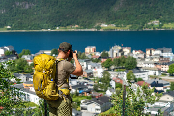 young blonde bearded backpacker and hiker tourist and photographer in Norway taking pictures of the stunning landscape