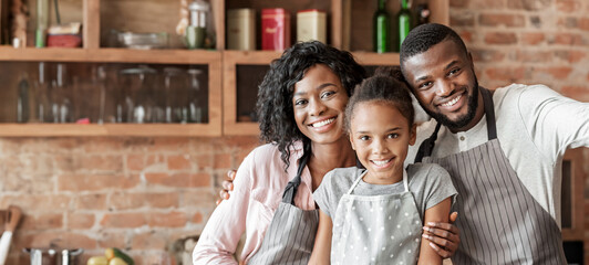 Happy african family taking selfie at kitchen, wearing aprons and smiling at camera