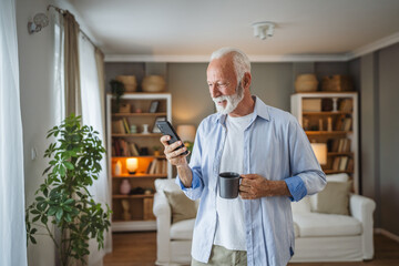portrait of senior man stand hold cup of coffee and use mobile phone