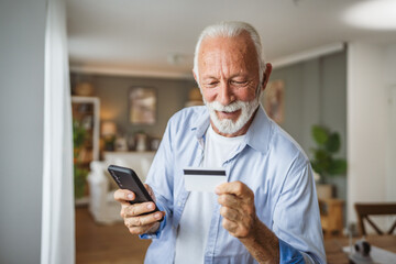 senior man buy online on mobile phone and use credit card at home