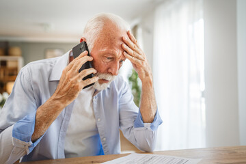 Senior man sit at home have a phone call while receive bad report
