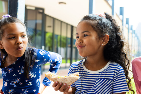 In a school setting, a young Hispanic girl enjoys a slice of pizza