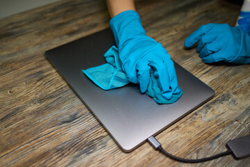 Maintaining laptop hygiene and care with gloves for cleanliness and technology preservation