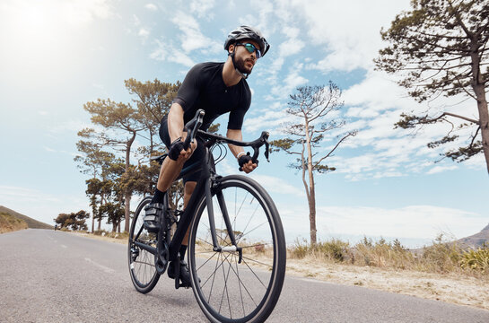 Road, cyclist or man in speed for training, competition and cycling race with endurance in Denmark. Outdoor, athlete and helmet for safety, fitness wellness and bike for sports adventure with energy