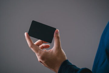 Hand holding a blank black card. Perfect for business concepts, advertising, invitations, or ID mockups. Professional and minimalist design.