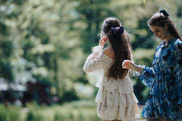 Carefree young girls in a lush park during spring, enjoying free time and expressing sisterhood and...