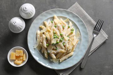 Delicious pasta with green peas, cheese and creamy sauce on grey table, top view