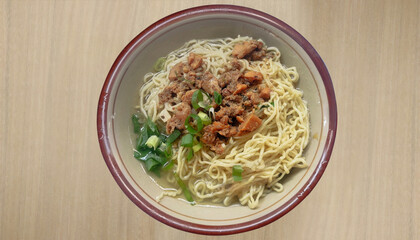 chicken noodles served in a bowl with pieces of sweetly stewed chicken, with a little broth and a sprinkling of celery served warm isolated on soft colored wooden texture background