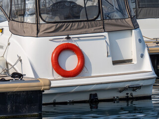 An orange life preserver ring on the stern of a motor yacht at a dock