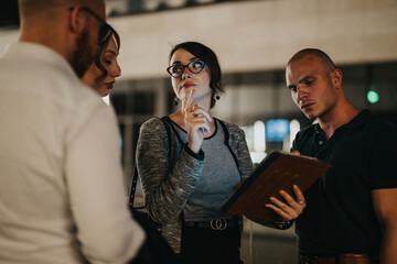 Young professionals in a night business meeting discussing work while using a digital tablet for collaboration.