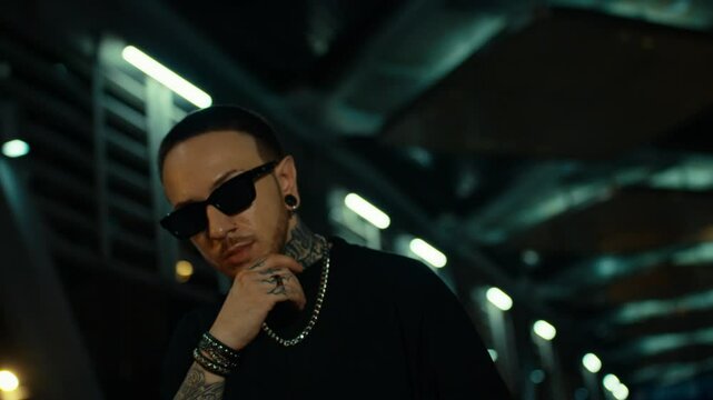tattoo guy with sunglasses, posing for the camera, hanging out in underground subway station, green lights