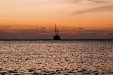 Obraz premium Cruise ship on the sea with sunset over the horizon line