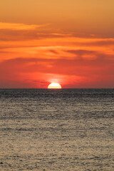 The vast ocean with the setting sun above the horizon line