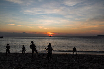 silhouette of family people playing on the beach with sunset background