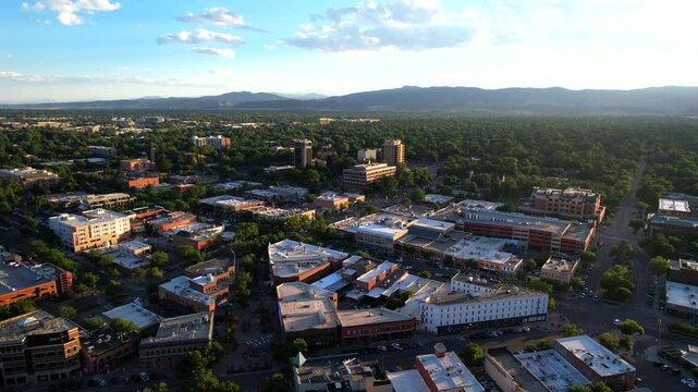 Aerial Drone Reverse to reveal the town of Fort Collins Colorado at sunset with mountains in the background