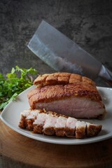 Crispy pork in white ceramic plate with cleaver knife and cutting borad with coriander , asian food