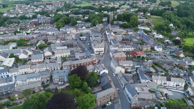 Drone fly-up exterior view of Holsworthy town centre, highlighting its central buildings and surrounding residential areas, Devon, United Kingdom