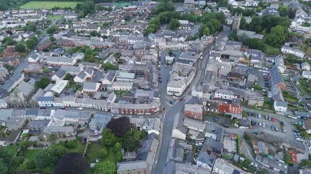 Drone orbital view of Holsworthy town centre on a summer afternoon, emphasizing the town's unique layout and green surroundings, Devon, United Kingdom