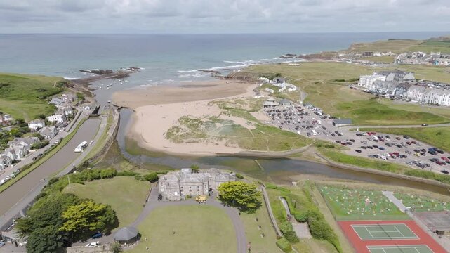 Aerial establishing shot of Summerleaze Beach in Bude, Cornwall, showing the beach's layout, car parks, surrounding buildings, and the beachgoers enjoying the sunny weather