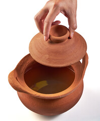 Hand holding the clay pot lid (earthenware pot) and open isolated on white background. Pottery is the process of making containers out of clay and burning. Vintage, Retro and Antique Kitchenware.