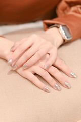 Close up of elegant hands with shiny silver nail polish, showcasing a sophisticated and stylish manicure.