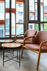 Comfortable seating area with pink chairs and small round tables near large windows.