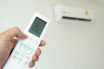 Hand with remote control directed on the conditioner at room