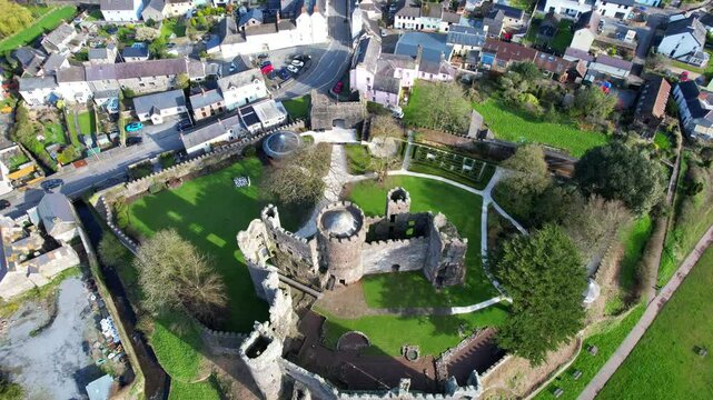 Aerial pullback shot of Laugharne Castle ruins during sunny day in Carmarthenshire, Wales