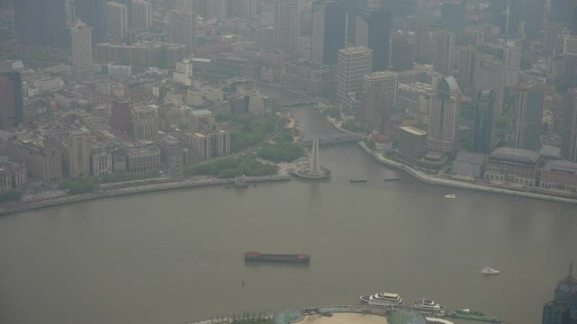 High angle view of smog over Waitan District and Huangpu River with cargo ship and some boats navigating. Shanghai, China
