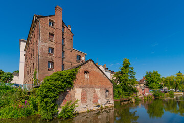 Fototapeta premium Louviers, France 07 19 2024 : Red brick building along the Eure river in the Center of Louvier in Normandy
