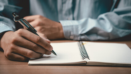 Male hand taking notes on the notepad. businessman working at work table, checklist writing planning investigate enthusiastic concept. focus on man hand holding pen, putting signature at official pape