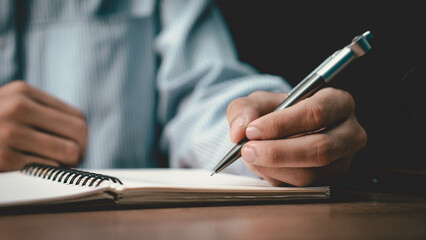 Male hand taking notes on the notepad. businessman working at work table, checklist writing planning investigate enthusiastic concept. focus on man hand holding pen, putting signature at official pape