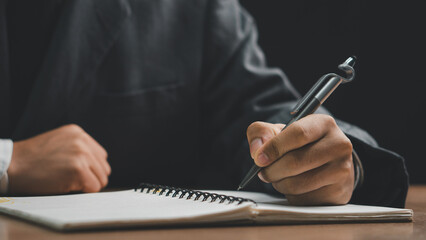 Male hand taking notes on the notepad. businessman working at work table, checklist writing planning investigate enthusiastic concept. focus on man hand holding pen, putting signature at official pape