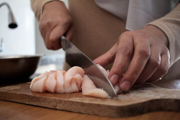 Obraz premium Asian muslim woman cutting chicken breast meat. Meal preparation