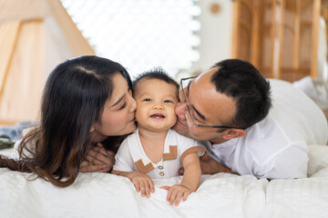 Portrait of enjoy happy love family asian father and mother playing with adorable little asian baby.newborn, infant.dad touching with cute son moments good time in a white bedroom.Love of family