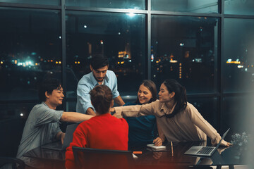 Successful businesspeople putting hands together at modern office with night city view. Group of businesspeople with stacks of hands. Represent teamwork, trust, unity, partnership, teamwork. Tracery.