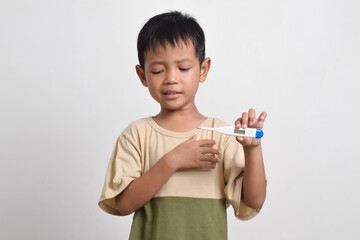 Little sick Asian boy holding thermometer isolated on white background. healthcare concept