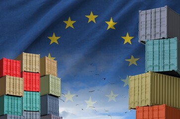 European union flag and big stack of shipping cargo containers in docks with sky background close up