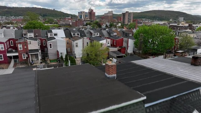 Colorful row of houses in dense populated housing area in USA. Aerial flight Over roof and homes during cloudy day. Reading City, PA, USA.