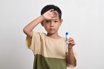 Sick little Asian boy holding thermometer and hand on forehead isolated on white background. health concept