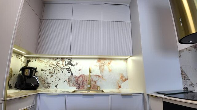 Luxurious interior. New kitchen in a small apartment. Gray, gold and sintered quartz