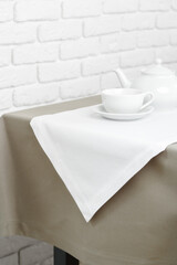 Beige Tablecloth on White Brick Wall With Teacups and Teapot