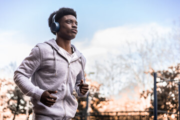 African man running outdoors. Sky copyspace.