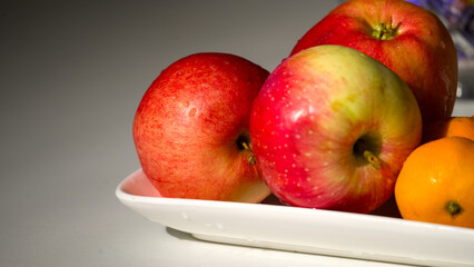 A white plate with a few apples and oranges on it