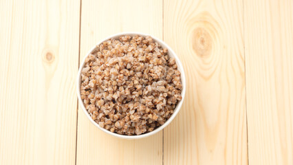 buckwheat porridge in a round white plate on a wooden table.