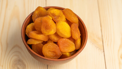 Dried Fruits wooden table. Dried apricots in a clay cup on a wooden background